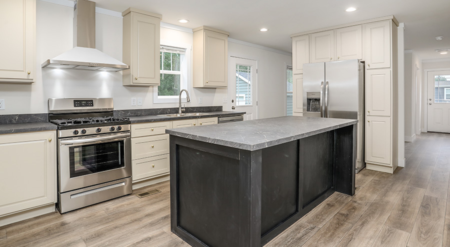 Modern manufactured home kitchen at The Reserves featuring a large island, white cabinetry, stainless steel appliances, and recessed lighting