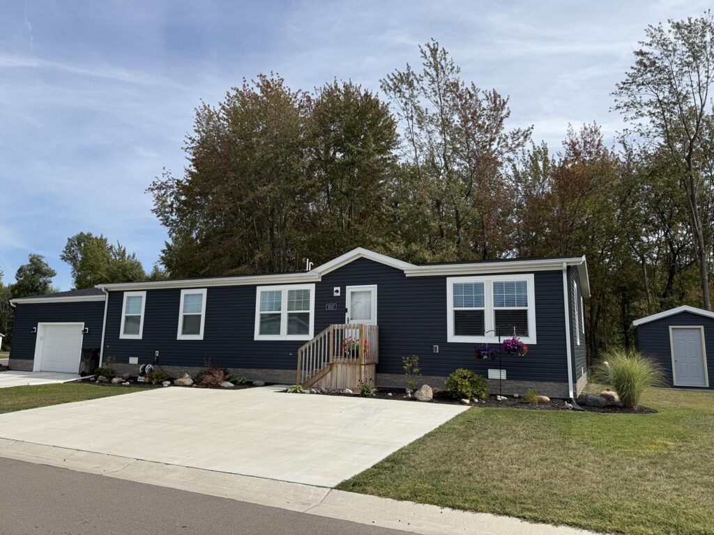 Single-story manufactured home with attached garage and paved driveway at The Reserves community in Jackson, Michigan
